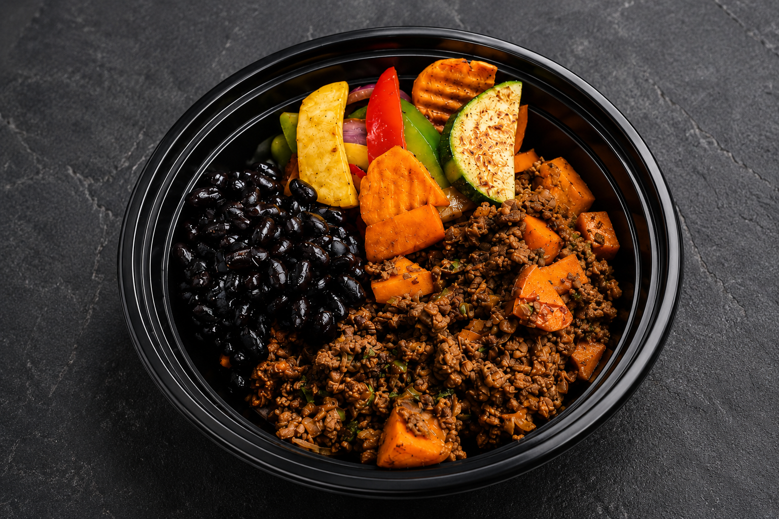 Lean beef picadillo with black beans, roasted sweet potato and sautéed vegetables in a meal prep bowl